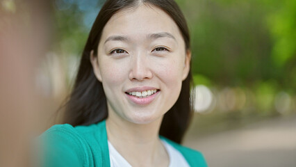 Young chinese woman smiling confident making selfie with camera at park