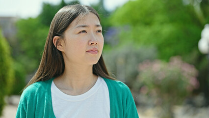 Young chinese woman looking to the side with serious expression at park