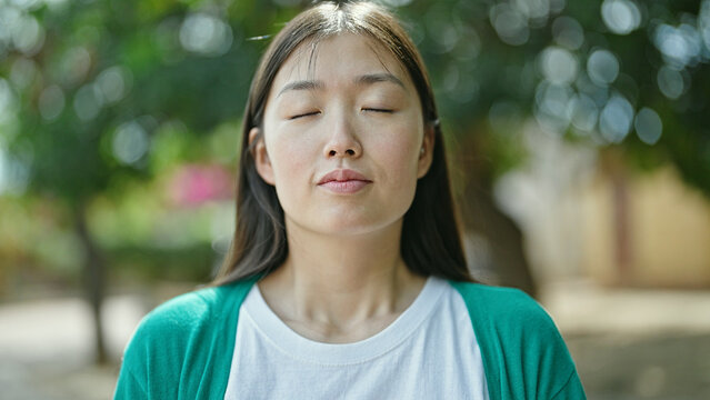 Young Chinese Woman Breathing With Closed Eyes At Park