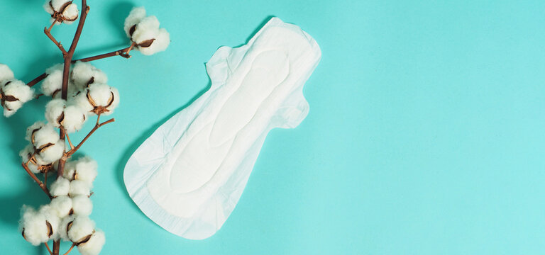 Sanitary napkin with wings and cotton flowers on mint green color or Tiffany Blue background.