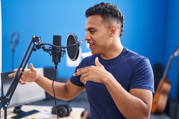 Young latin man artist singing song at music studio