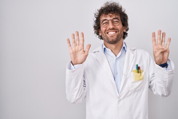 Hispanic young man wearing doctor uniform showing and pointing up with fingers number nine while smiling confident and happy.