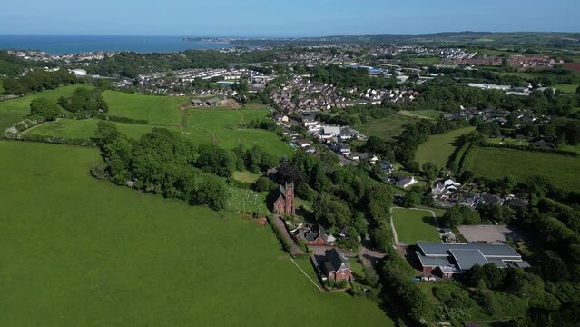 Collaton St Mary, South Devon, England: DRONE VIEWS: The drone pulls away from St Mary church and the village of Collaton St. Mary to show green belt land; Paignton & Torbay sea are in the background.