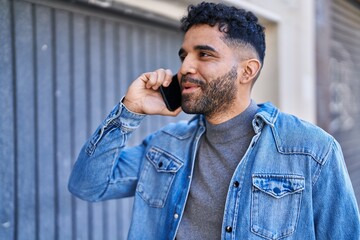 Young hispanic man smiling confident talking on the smartphone at street