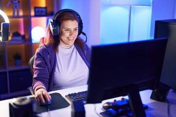 Young beautiful plus size woman streamer playing video game using computer at gaming room © Krakenimages.com
