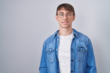 Fototapeta premium Caucasian blond man standing wearing glasses winking looking at the camera with sexy expression, cheerful and happy face.