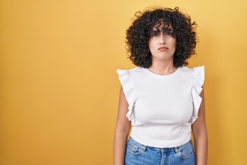 Young middle east woman standing over yellow background skeptic and nervous, frowning upset because of problem. negative person.