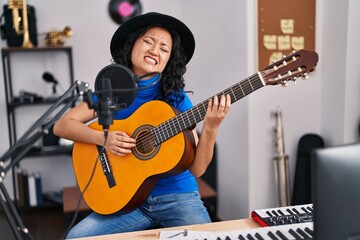 Fototapeta na wymiar Young chinese woman artist singing song playing guitar at music studio