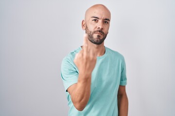 Middle age bald man standing over white background showing middle finger, impolite and rude fuck off expression