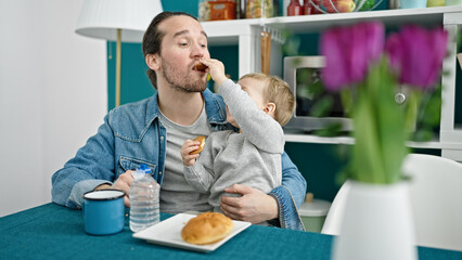 Father and son sitting on table having breakfast at dinning room