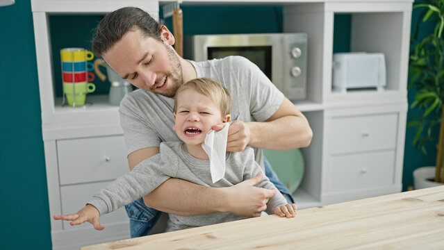 Father and son sitting on table cleaning face crying at dinning room