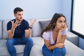 Young hispanic couple arguing sitting on sofa at home