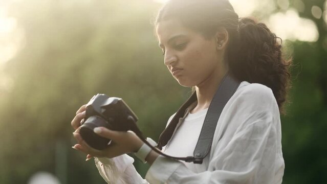 Portrait of sad young indian woman photographer dissatisfied her photos at camera and expressively delete it outdoors Lack of inspiration and creative crisis concept