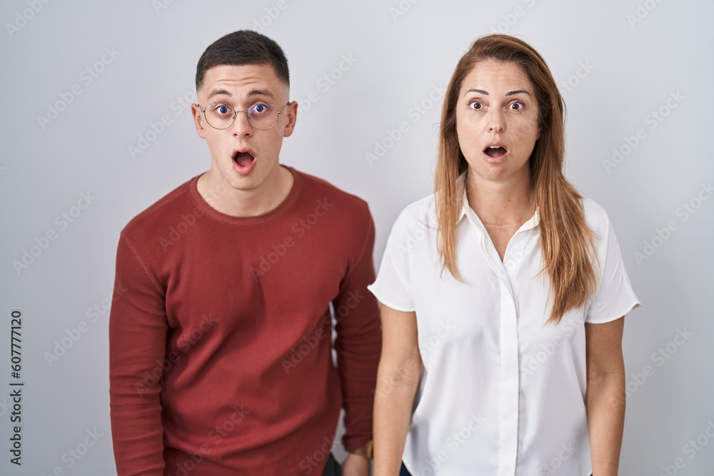 Poster Mother and son standing together over isolated background afraid and shocked with surprise and amazed expression, fear and excited face.