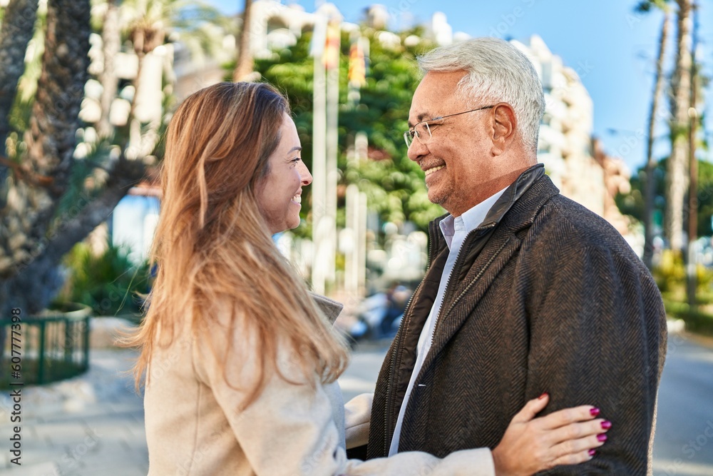 Poster Middle age man and woman couple hugging each other standing at street