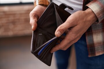 Young man showing empty wallet at office