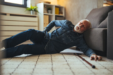  Senior man falling on the ground with walker in living room at home. Elderly older mature male...