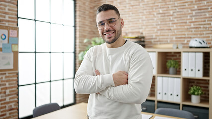 Fototapeta na wymiar Young hispanic man business worker smiling confident standing with arms crossed gesture at office