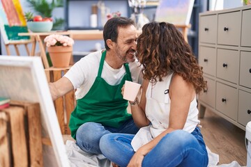 Man and woman artists drinking coffee drawing at art studio