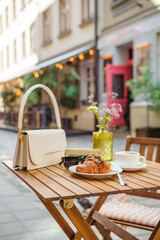 Handbag with glasses, croissant and coffee on the summer terrace