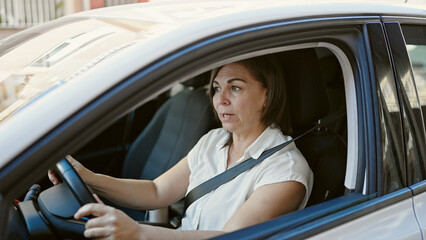Fototapeta na wymiar Middle age hispanic woman driving car at street