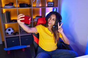 Fototapeta na wymiar Young beautiful arab woman streamer smiling confident make selfie by smartphone at gaming room