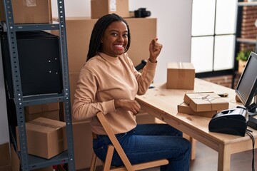 Young african american with braids working at small business ecommerce screaming proud, celebrating...