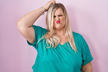 Caucasian plus size woman standing over pink background confuse and wondering about question. uncertain with doubt, thinking with hand on head. pensive concept.