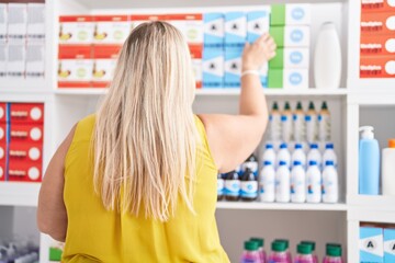 Young woman customer looking shelving on back view at pharmacy