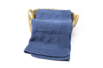 Navy blue wool knitted blanket in harlequin knitting pattern in a basket on a white background