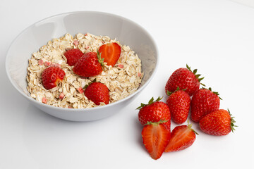 Fresh healthy breakfast of oatmeal and cereal with strawberries in a blue bowl on a white background isolate