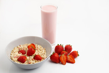 Fresh and healthy breakfast of Strawberry Yogurt, oatmeal with different cereals and strawberries on a white table with a white background and reflection and space for text
