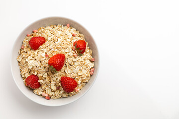 Fresh healthy breakfast of oatmeal and cereal with strawberries in a blue bowl on a white background isolate