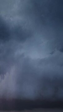 Lot of lightning during a thunderstorm. Storm clouds are moving fast on the viewer, timelapse. Vertical video