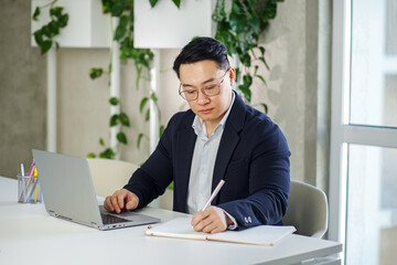 Fototapeta premium Asian businessman working in office, using laptop. Human resources. Finance concept. Multiracial