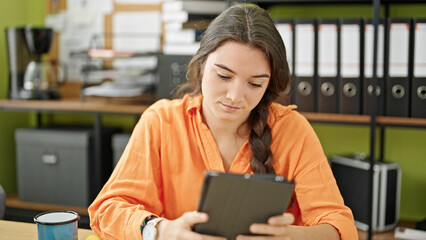 Fototapeta premium Young beautiful hispanic woman business worker using touchpad working at office