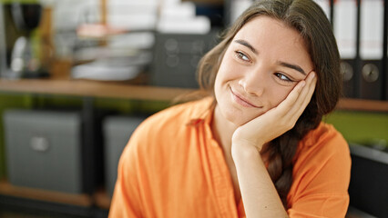 Young beautiful hispanic woman business worker smiling confident sitting on table at office