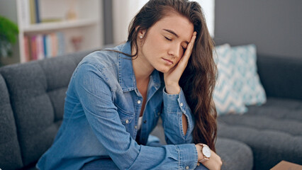 Fototapeta premium Young beautiful hispanic woman sitting on sofa with serious expression at home