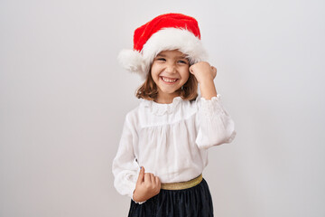 Little hispanic girl wearing christmas hat celebrating surprised and amazed for success with arms raised and eyes closed