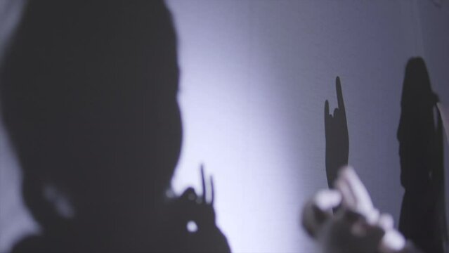 Close up of little girl happy playful family plays in shadow theater. Shadows on the wall
