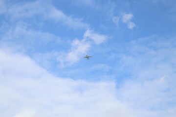 passenger airplane is flying in the blue sky with white clouds
