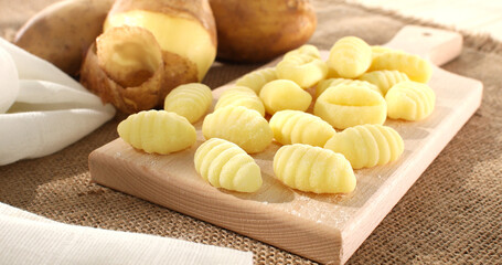Uncooked gnocchi on cutting board. italian potato noodles on a wooden background. traditional mediterranean cuisine. famous italian potato dish. food on a rustic table on a sunny day.