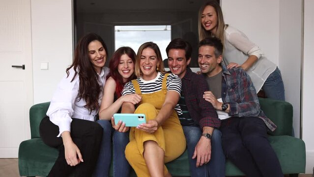 group of diverse friends are at home having fun on the sofa, with smart phone they take a selfie photo for social media