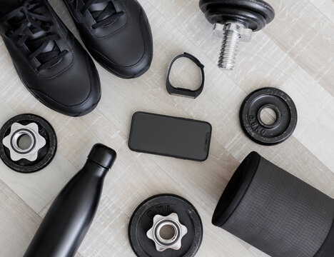 Flat lay of mobile phone and sport equipment on wooden floor