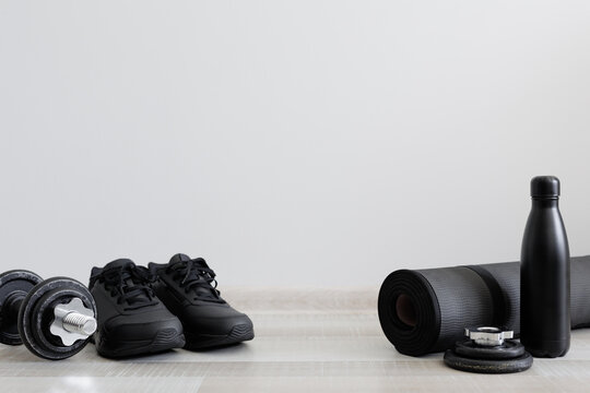 Fitness theme with dumbbells, sport shoes and water bottle on wooden floor