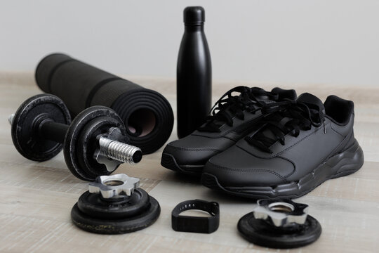 Sport theme with dumbbells, sports mat, shoes and water bottle on wooden floor