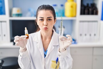 Young woman doing weed oil extraction at laboratory looking at the camera blowing a kiss being lovely and sexy. love expression.