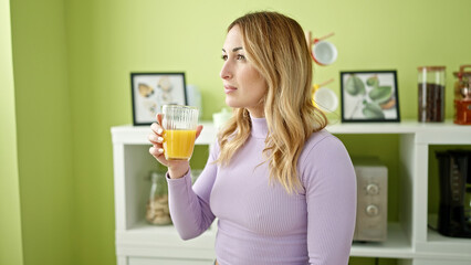 Young beautiful hispanic woman drinking juice at dinning room