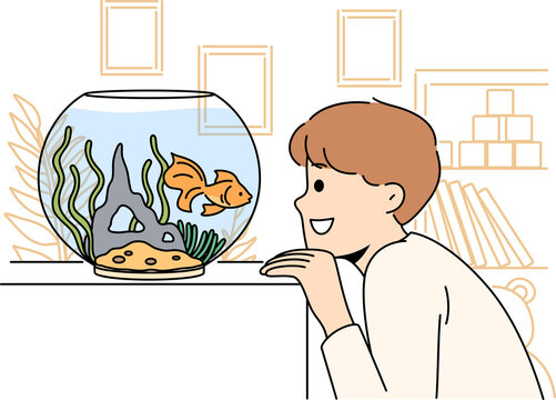 Smiling child look at goldfish in tank