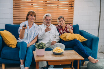 Members of the family from multiple generations enjoy quality time together by watching television, sharing snacks and conversation, discovering new areas of interest, and cultivating stronger bonds.